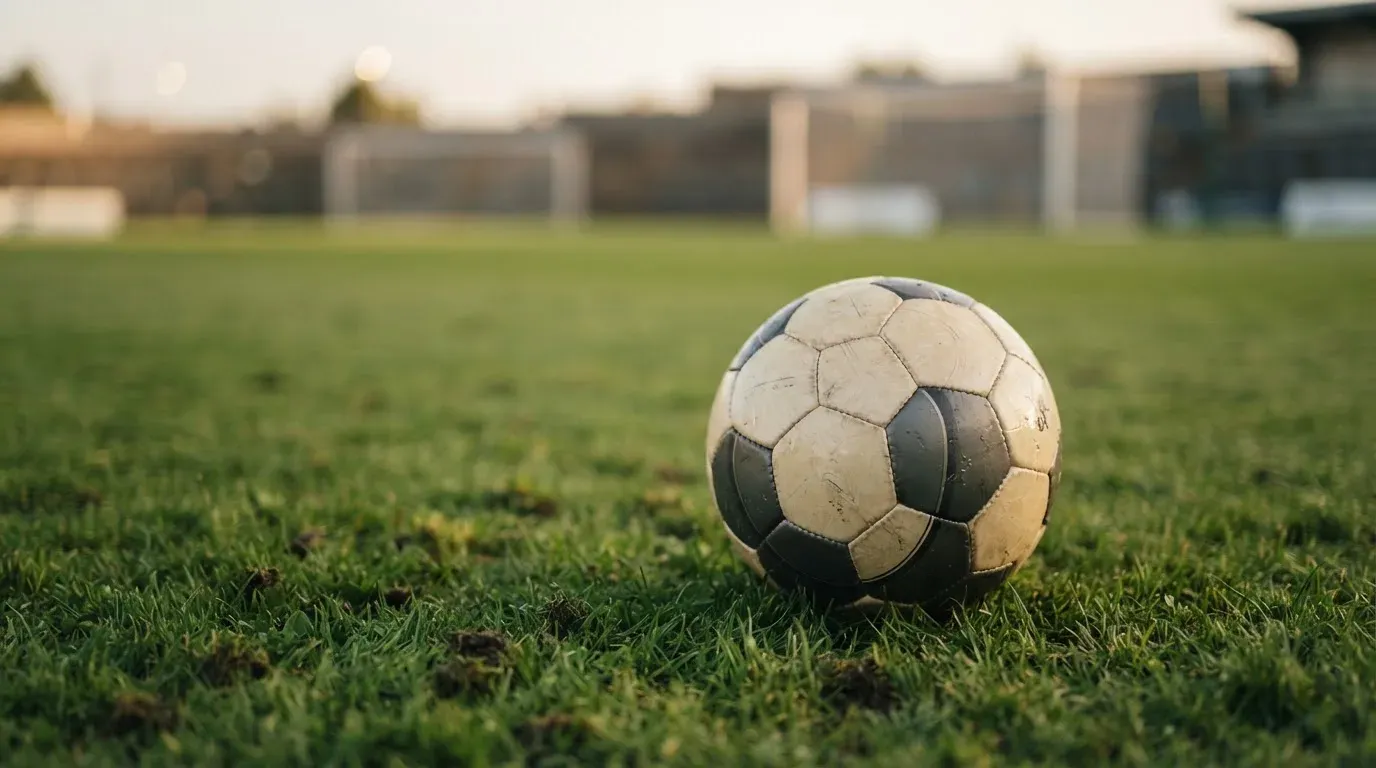 Ein Fussball auf dem Rasen aus niedriger Perspektive aufgenommen, die Torpfosten verschwimmen im Hintergrund.