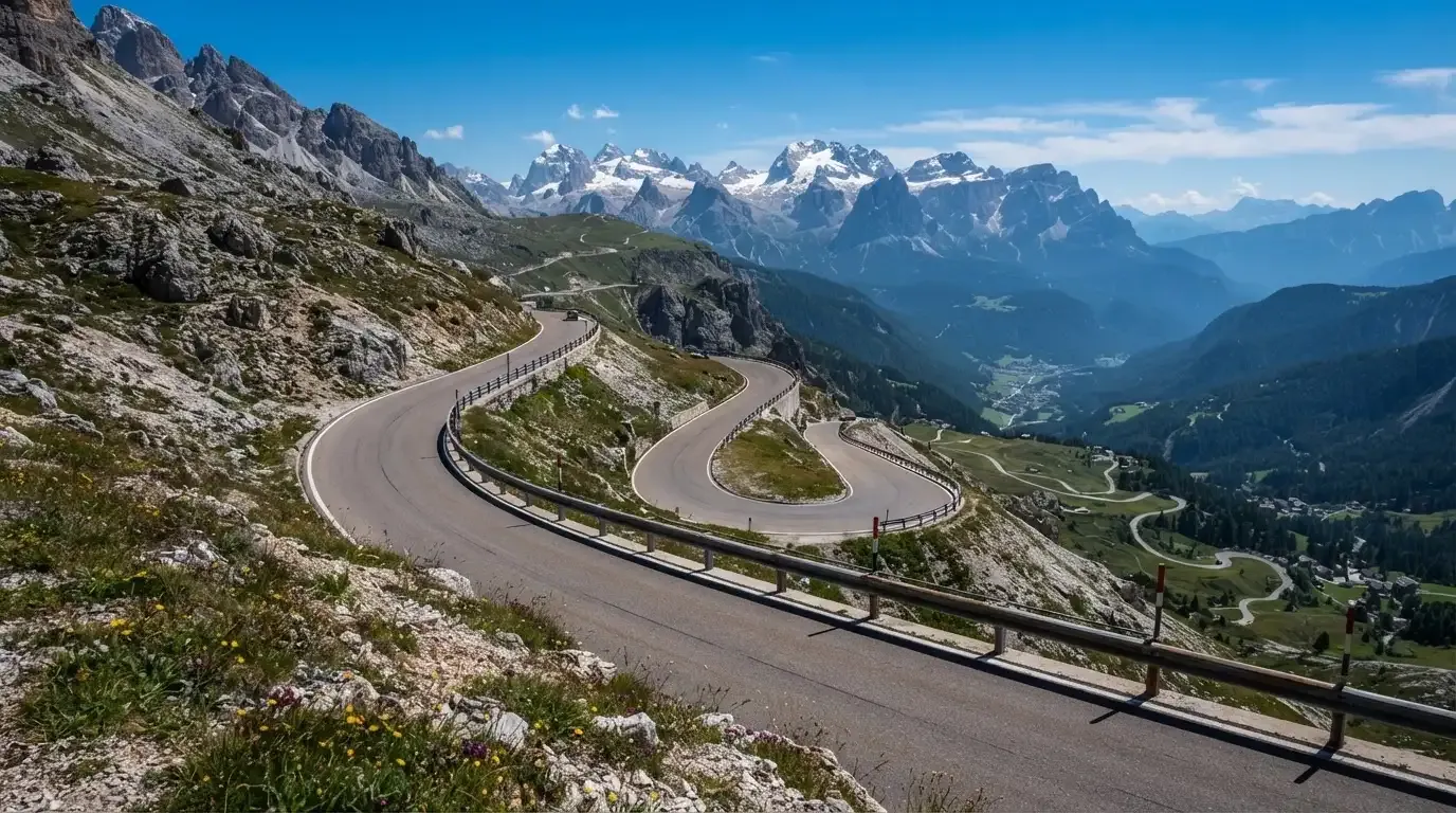 Eine Passstrasse mit Leitplanke windet sich an einem klaren Tag durch eine Berglandschaft.