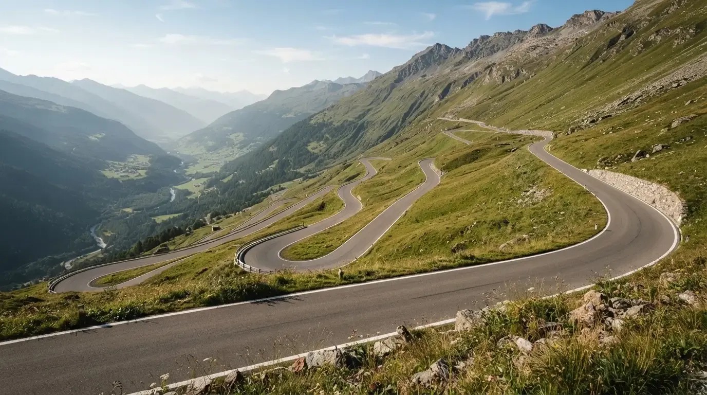 Eine Passstrasse zieht sich in Kehren einen Alpenhang hinauf, kein Fahrzeug ist zu sehen.
