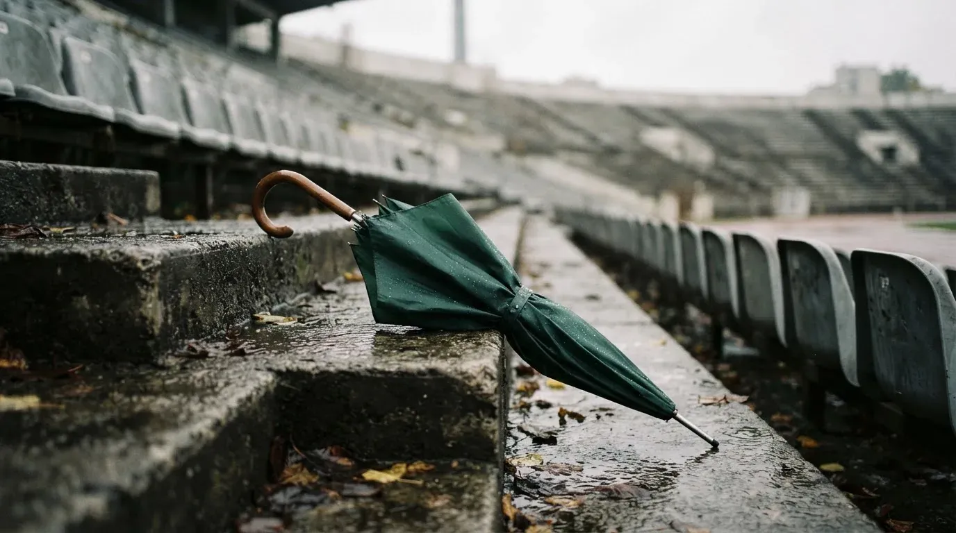 Ein Regenschirm liegt auf einer nassen Treppe zwischen leeren Zuschauerrängen.